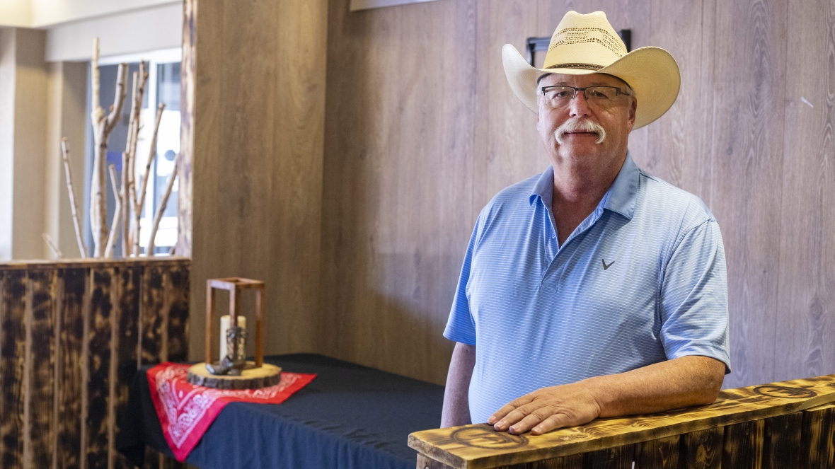 A man stands wearing a cowboy hat